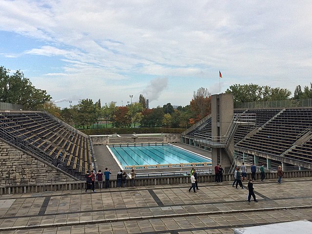 Olympic swimming pool with people walking by