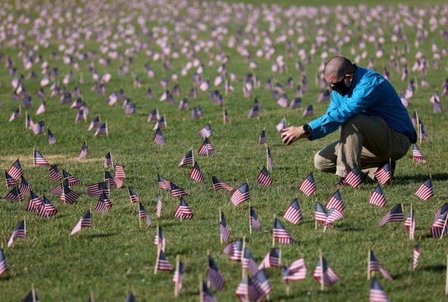 A man crouched down among the mini American flags at the National Mall in D.C.