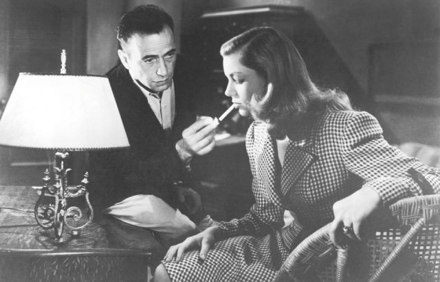 Humphrey Bogart (1899 - 1957) lights a cigarette for actress Lauren Bacall in a still from the film 'To Have and Have Not', directed by Howard Hawks, 1944. 