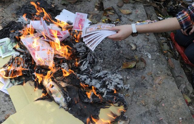 Chinese woman burns paper money as offerings at a cemetary on "Qingming" in Hefei, east China's Anhui province on April 3, 2012.
