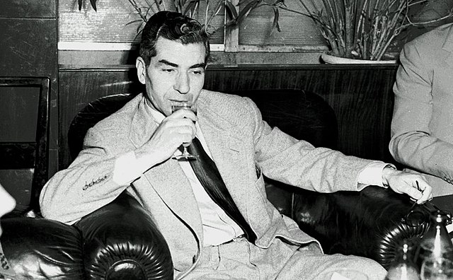 Mobster Lucky Luciano sitting on a leather chair and drinking wine