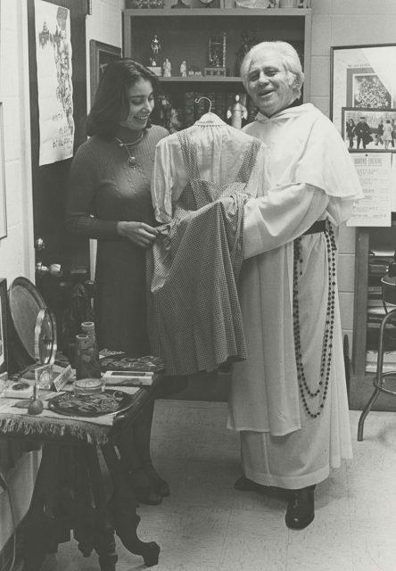 Reverend Gilbert Hartke showing Judy Garland's dress to a female student