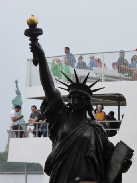 A ferry passes behind the miniature statue
