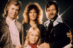 ABBA members standing in front of a spotlight