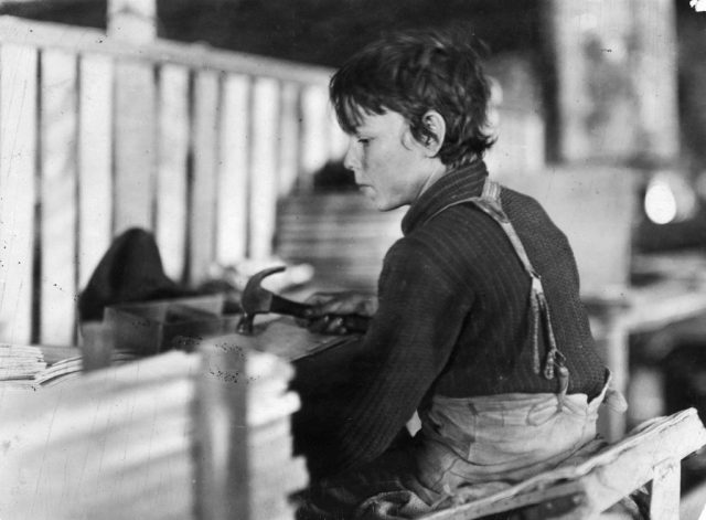 Young boy holding a hammer and sitting at a desk