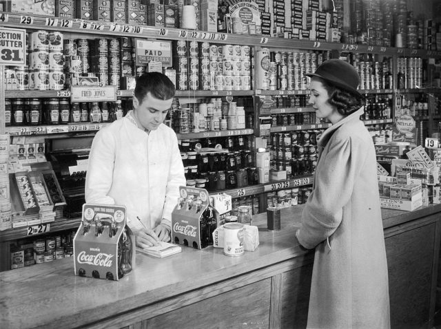 Woman purchasing two six packs of Coca-Cola from a grocery store