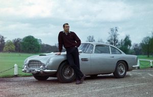 James Bond leaning against his Aston Martin D5B