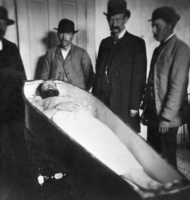 Men standing around Jesse James' coffin