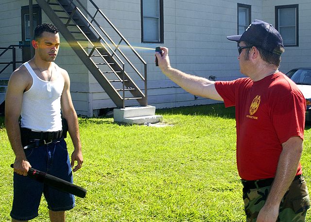 An instructor spraying pepper spray into the eyes of a fellow military member