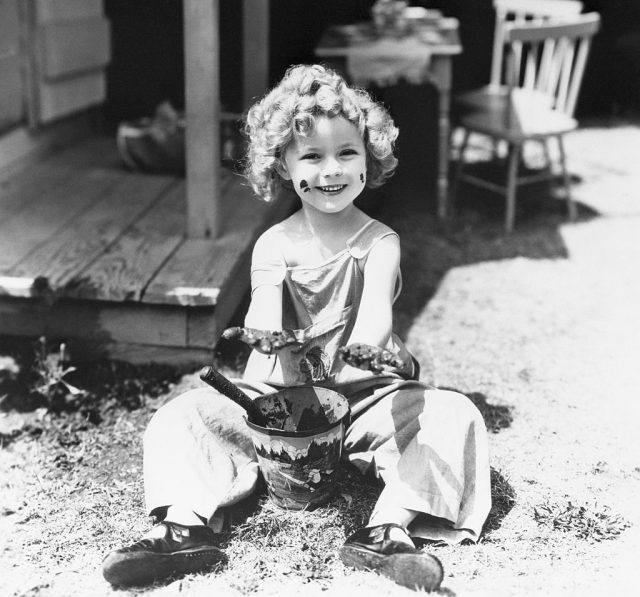 Shirley Temple playing with mud