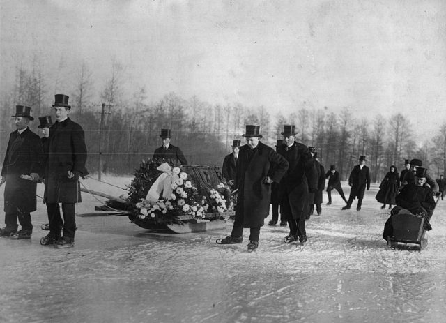 Men surrounding a coffin adorned with flowers