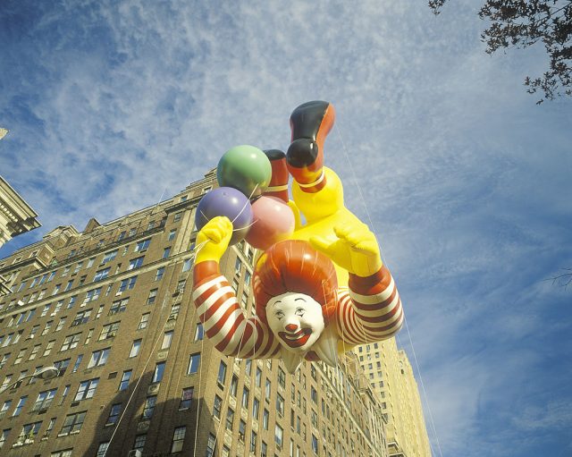 Ronald mcdonald balloon fronting in front of a brick apartment building