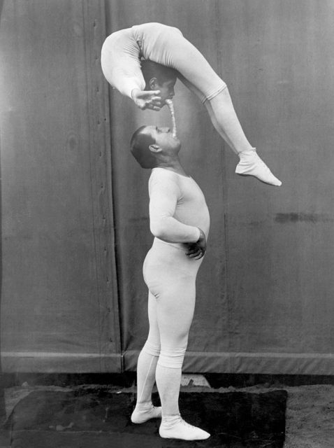 A circus performer balancing a contortionist over his head