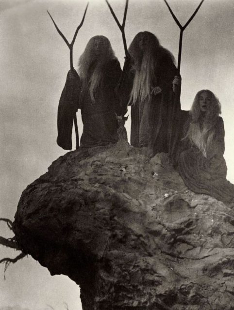 Three witches standing on a hill