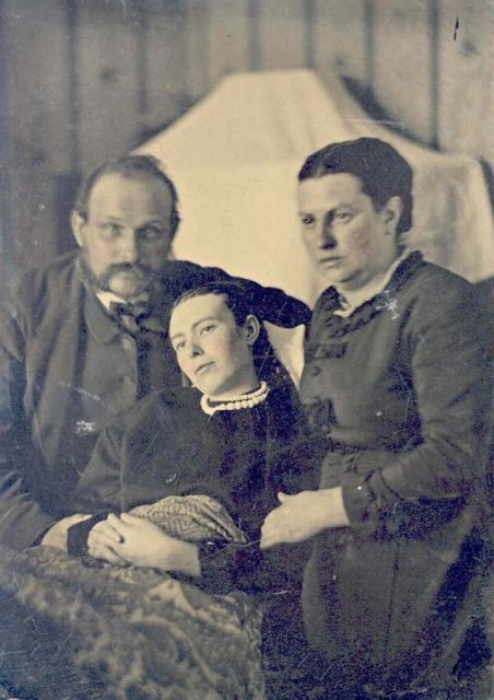 Parents sitting beside their deceased daughter during Victorian times