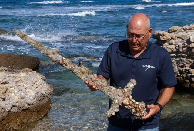 Man holding the Crusades sword by the Mediterranean Sea