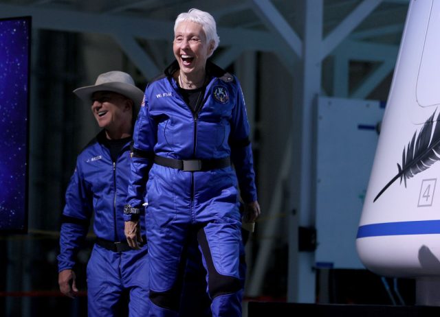 Blue Origin’s New Shepard crew (L-R) Jeff Bezos and Wally Funk arrive for a press conference after flying into space in the Blue Origin New Shepard rocket on July 20, 2021 (Photo Credit: Joe Raedle/Getty Images)