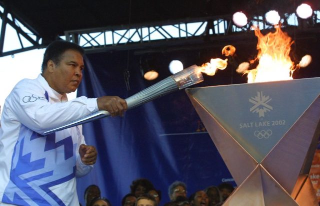 Former 1968 Olympic gold medalist Muhammad Ali lights the first torch to start the Olympic Torch Relay 04 December 2001, at Centennial Olympic Park in Atlanta, Georgia. AFP PHOTO/POOL/Chris STANFORD (Photo by Chris STANFORD / ALLSPORT / AFP) (Photo Credit: CHRIS STANFORD/AFP via Getty Images)