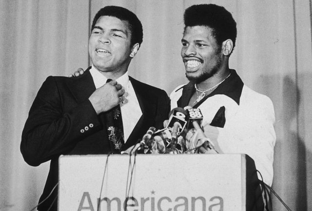 American boxers Muhammad Ali (left) and Leon Spinks smiling at a podium at a press conference at the Americana Hotel to announce their upcoming fight, New Orleans, Louisiana. (Photo Credit: Gary Settle/New York Times Co./Getty Images)