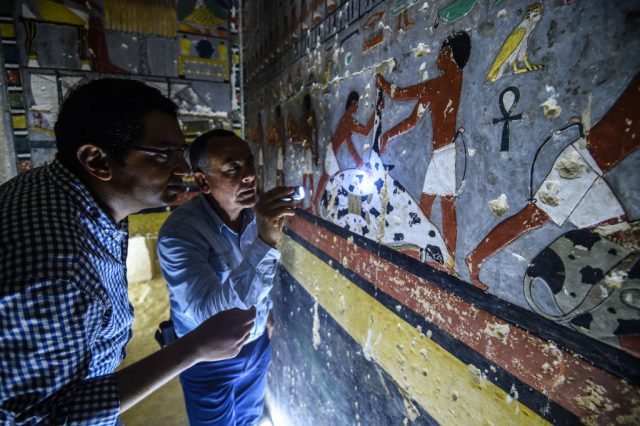 Two archaeologists examining hieroglyphics