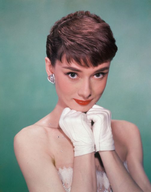 Audrey Hepburn resting her chin on her white-gloved hands