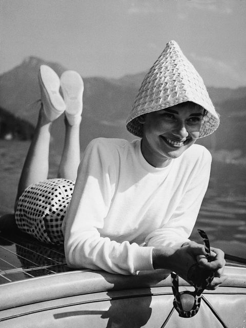 Audrey Hepburn wearing a hat and laying on her stomach