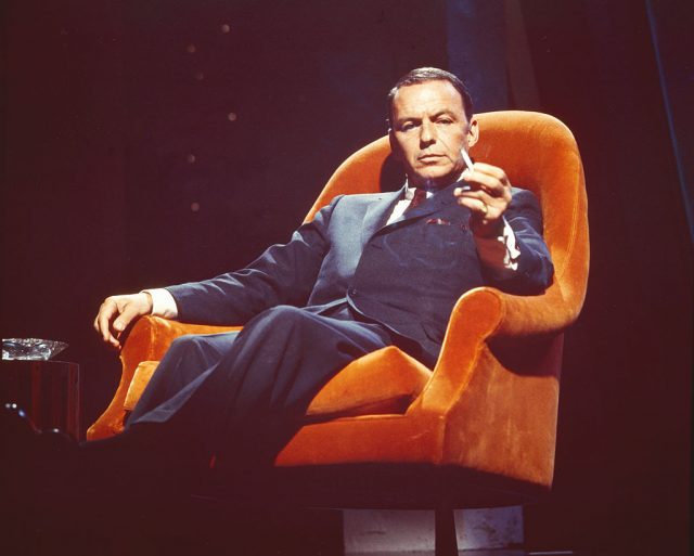 Frank Sinatra smoking a cigarette while sitting in an orange armchair