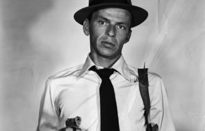 Frank Sinatra aiming a gun by his stomach