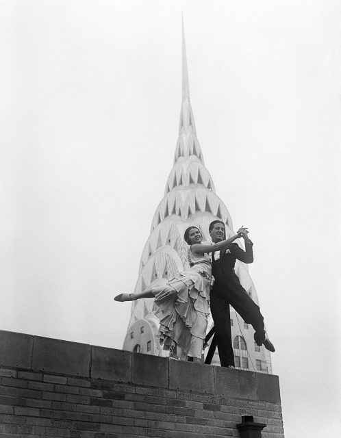 Quite a festive touch is lent to the majestic skyline of New York City, by Ramon and Rosita, internationally known dance artists, as they demonstrate the Southampton Hop, new Terpsichorean number, atop of the Chanin Building. The awe-inspiring and modernistic spire of the Chrysler Building looms in the background. (Photo Credit: Bettmann / Contributor)