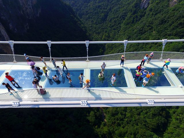 Tourists walk on the glass-floor suspension bridge on the first day of its trial operation on August 20, 2016 in Zhangjiajie, China. (Photo Credit: Feature China / Barcroft Media via Getty Images)