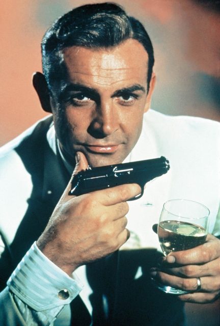 James Bond holding a handgun and a glass of wine