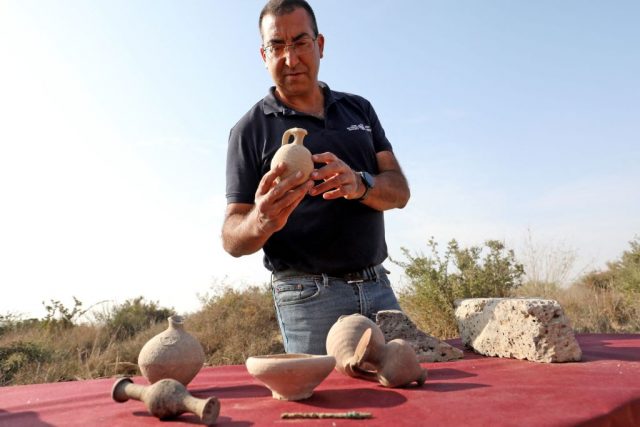 Saar Ganor examining a piece of pottery