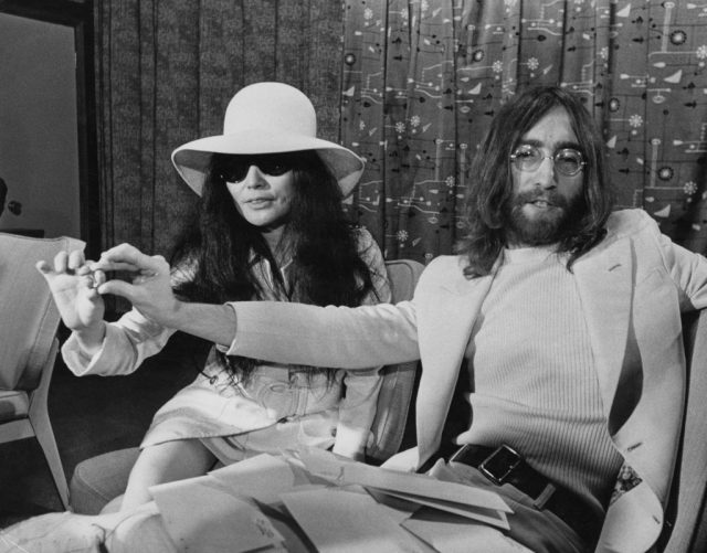 Yoko Ono and John Lennon sitting on a couch