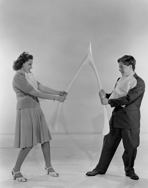 Judy Garland and Mickey Rooney pulling on a large wishbone