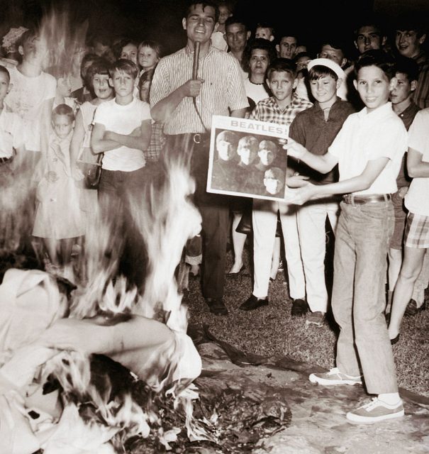 A crowd of teenagers burning albums by the Beatles