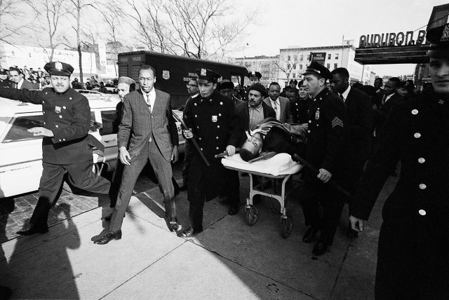 Police officers carrying a stretcher with Malcolm X