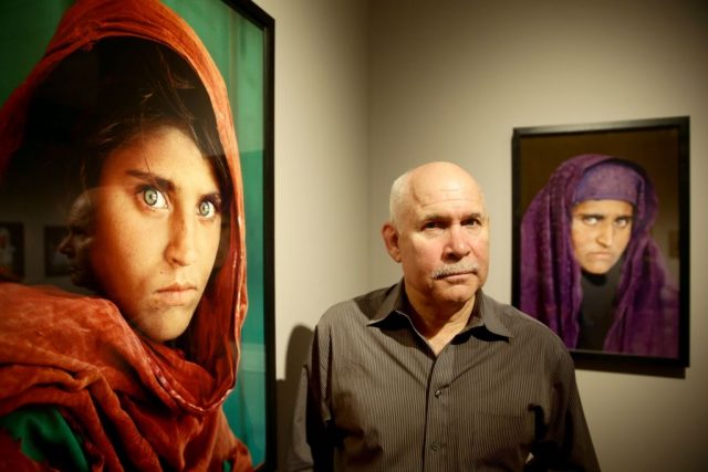 Steve McCurry standing beside an enlarged photograph of the 'girl with the green eyes'