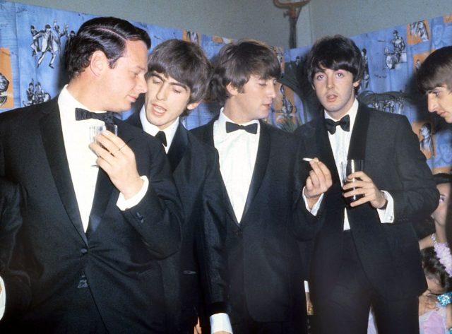 Brian Epstein standing beside the members of the Beatles