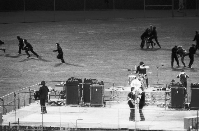 Policemen running fans off the field while the Beatles perform