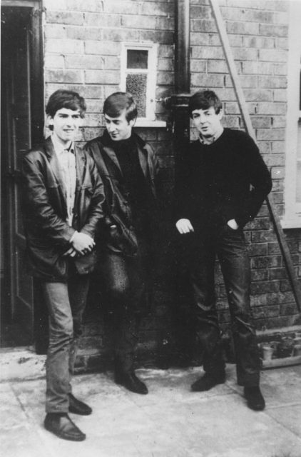 George Harrison, John Lennon and Paul McCartney leaning against a brick wall