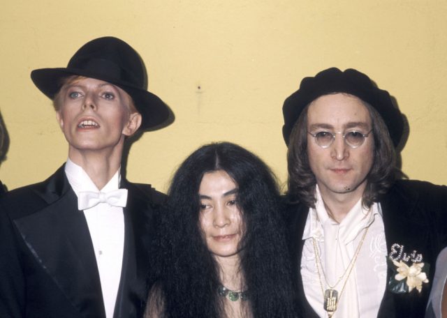 David Bowie, Yoko Ono and John Lennon standing in front of a yellow wall