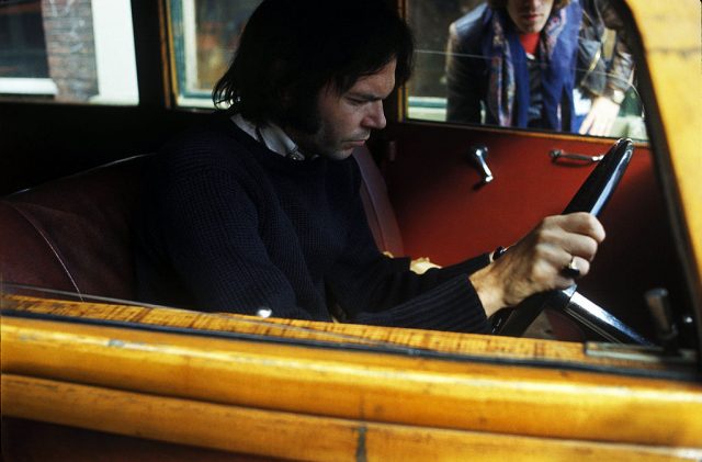 Neil Young sitting behind the wheel of a Rolls Royce