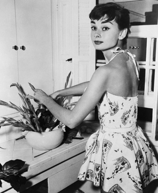 Audrey Hepburn arranging flowers in her kitchen 