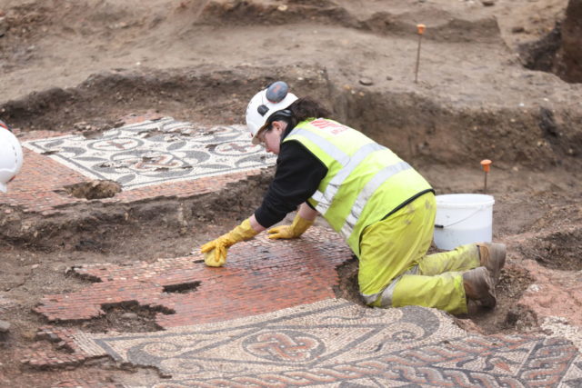 Archaeologist kneeling over the ancient Roman mosaic discovered in London