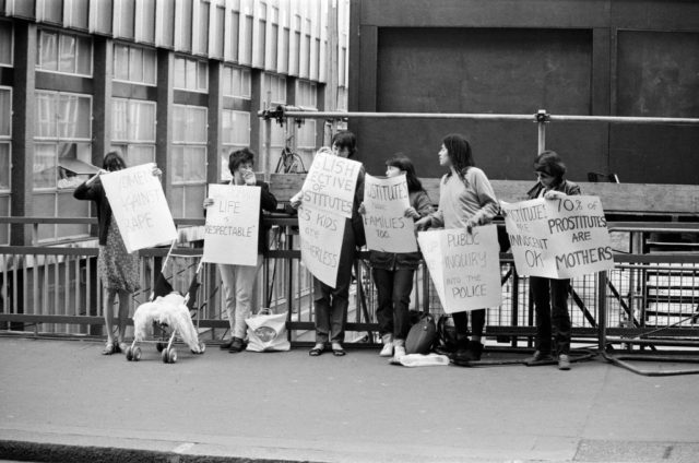 Women holding protest signs outside the trial of Peter Sutcliffe
