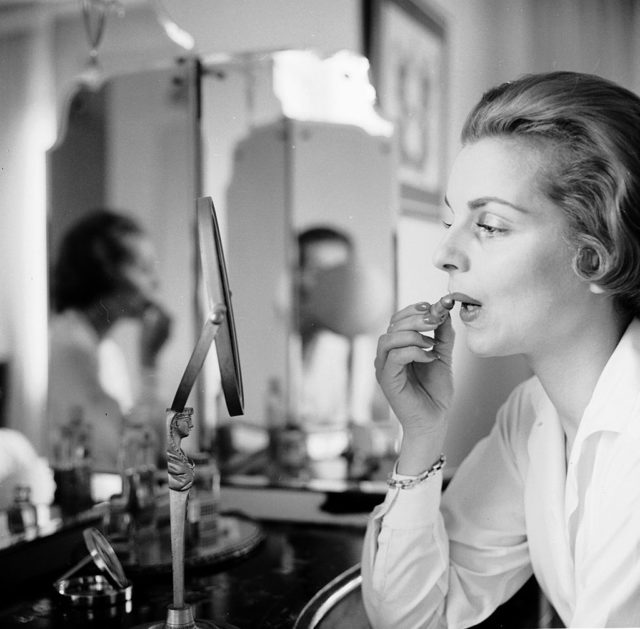 Woman applying makeup in front of a vanity mirror