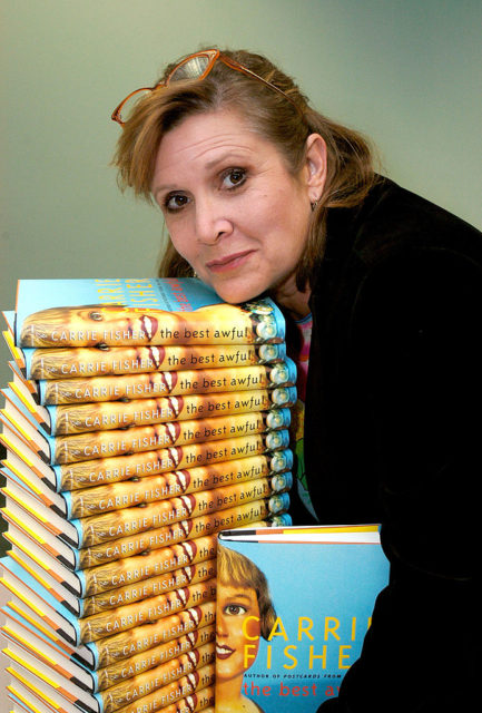 Carrie Fisher posing with a stack of her book in 2004