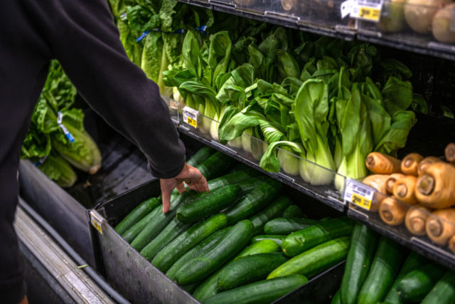 A shopper reaches for a vegetable at a modern Safeway store.