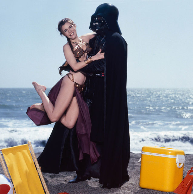 Carrie Fisher as Leia is held up by Darth Vader while on the beach