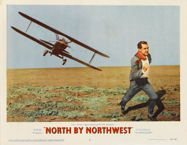 A lobby card photo for Alfred Hitchcock's movie North by Northwest features Cary Grant running from an inbound plane. 